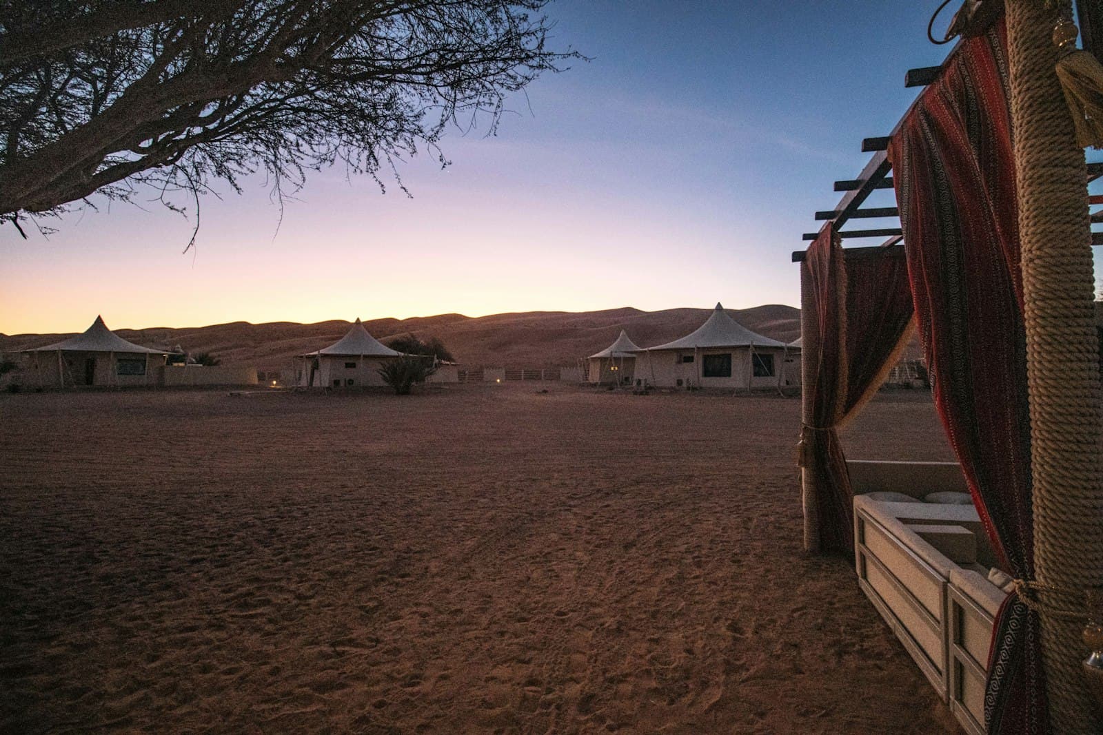 White canvas tents at a desert camp in the dunes at twilight