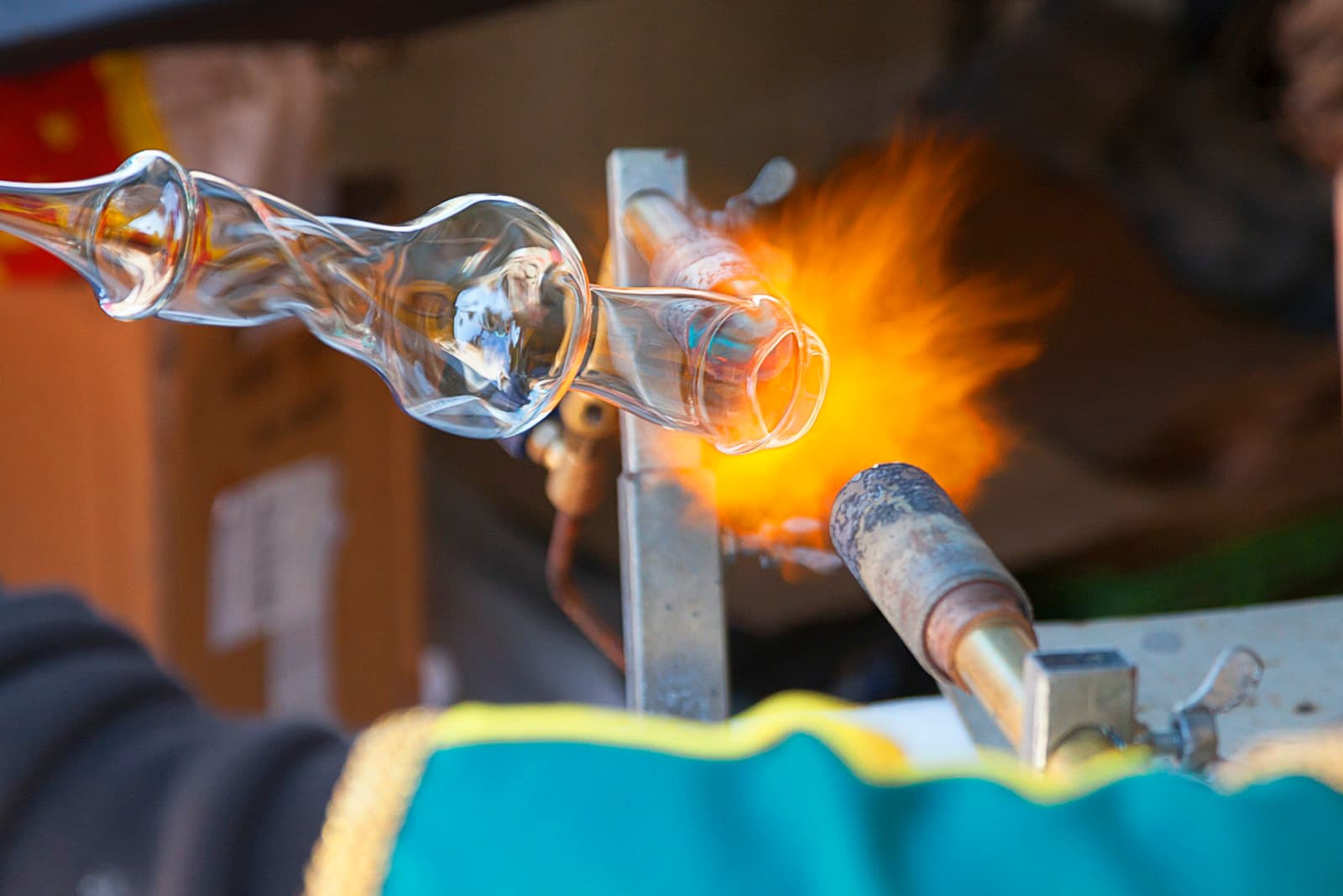 A glassmaker shaping a clear vessel in the flame of a torc